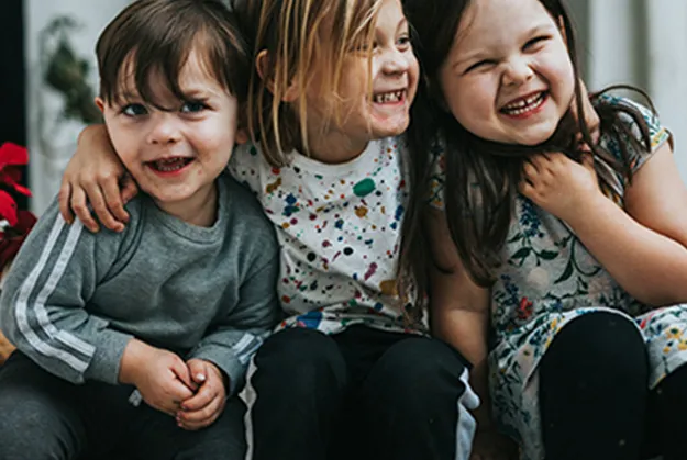 Kinder sitzen fröhlich auf einer Treppenstufe